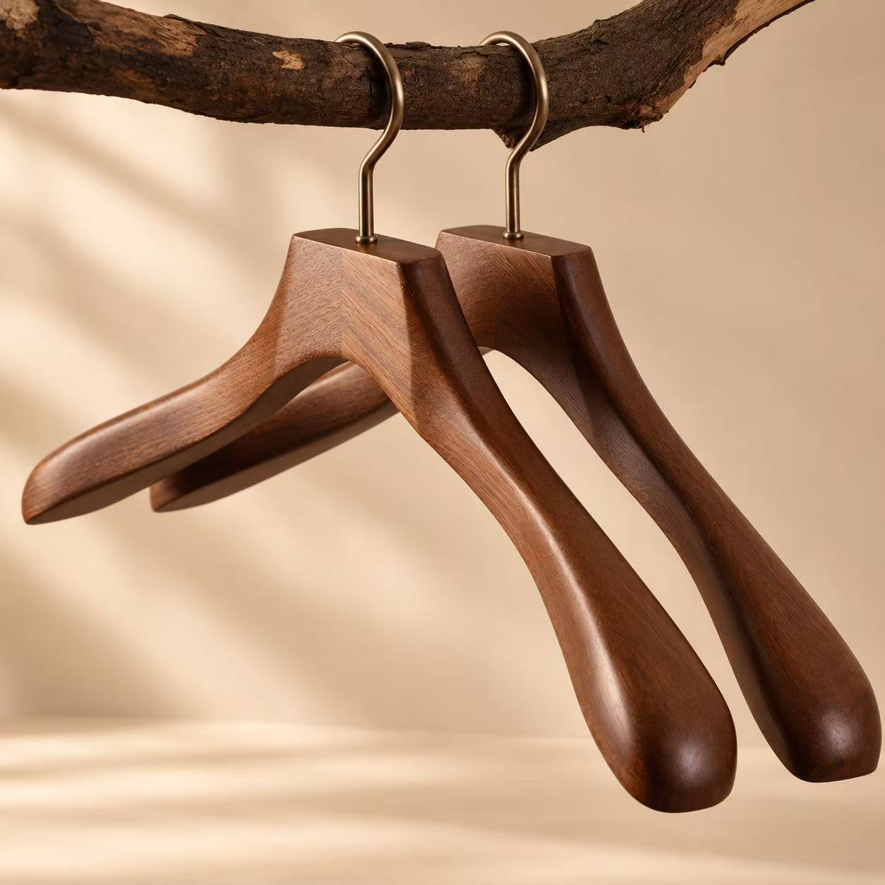 Wide-shoulder walnut-finish wooden coat hangers with brass hooks.