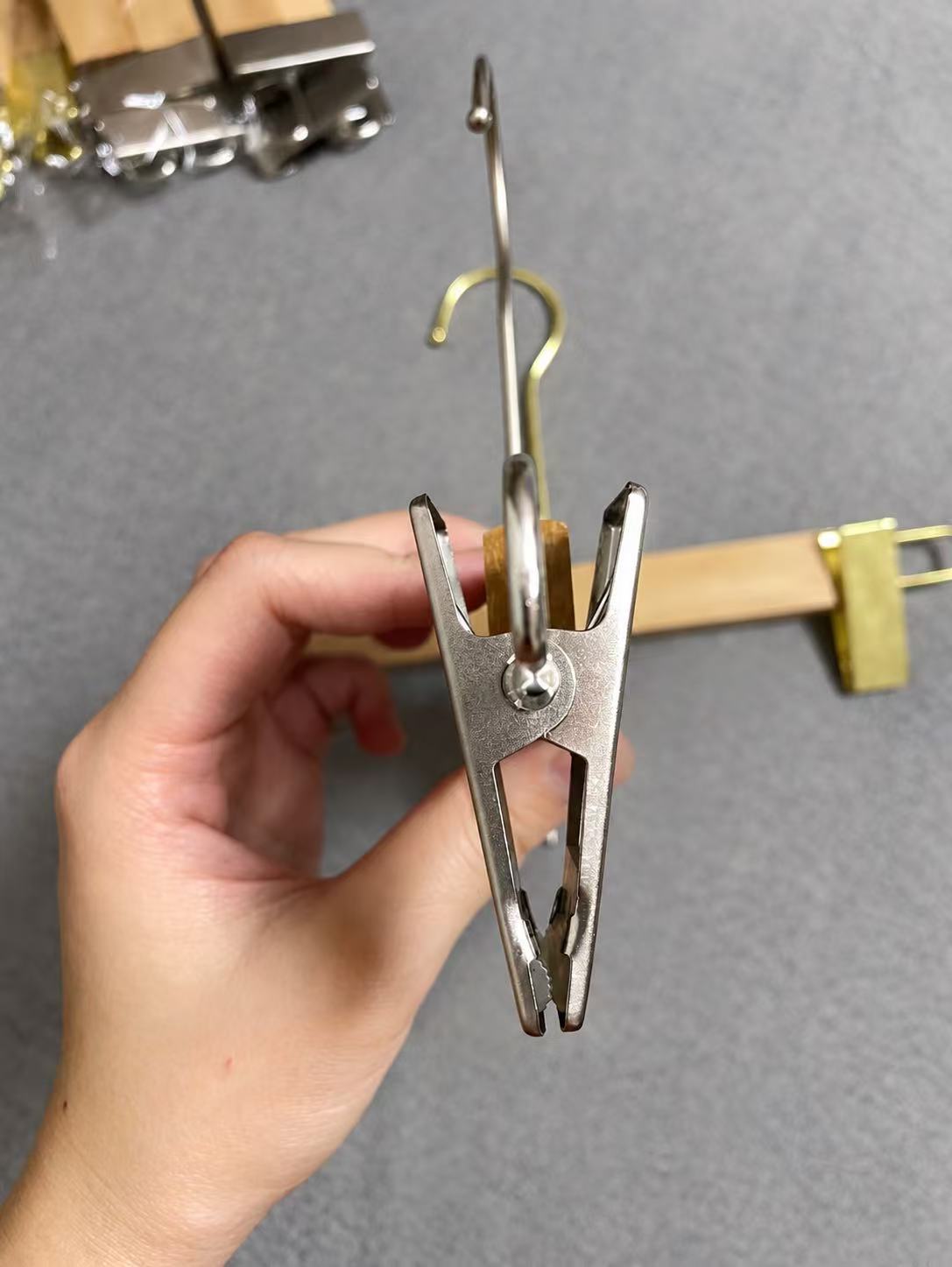 Close-up of a metal hanger clip with hooks and other hardware behind it.