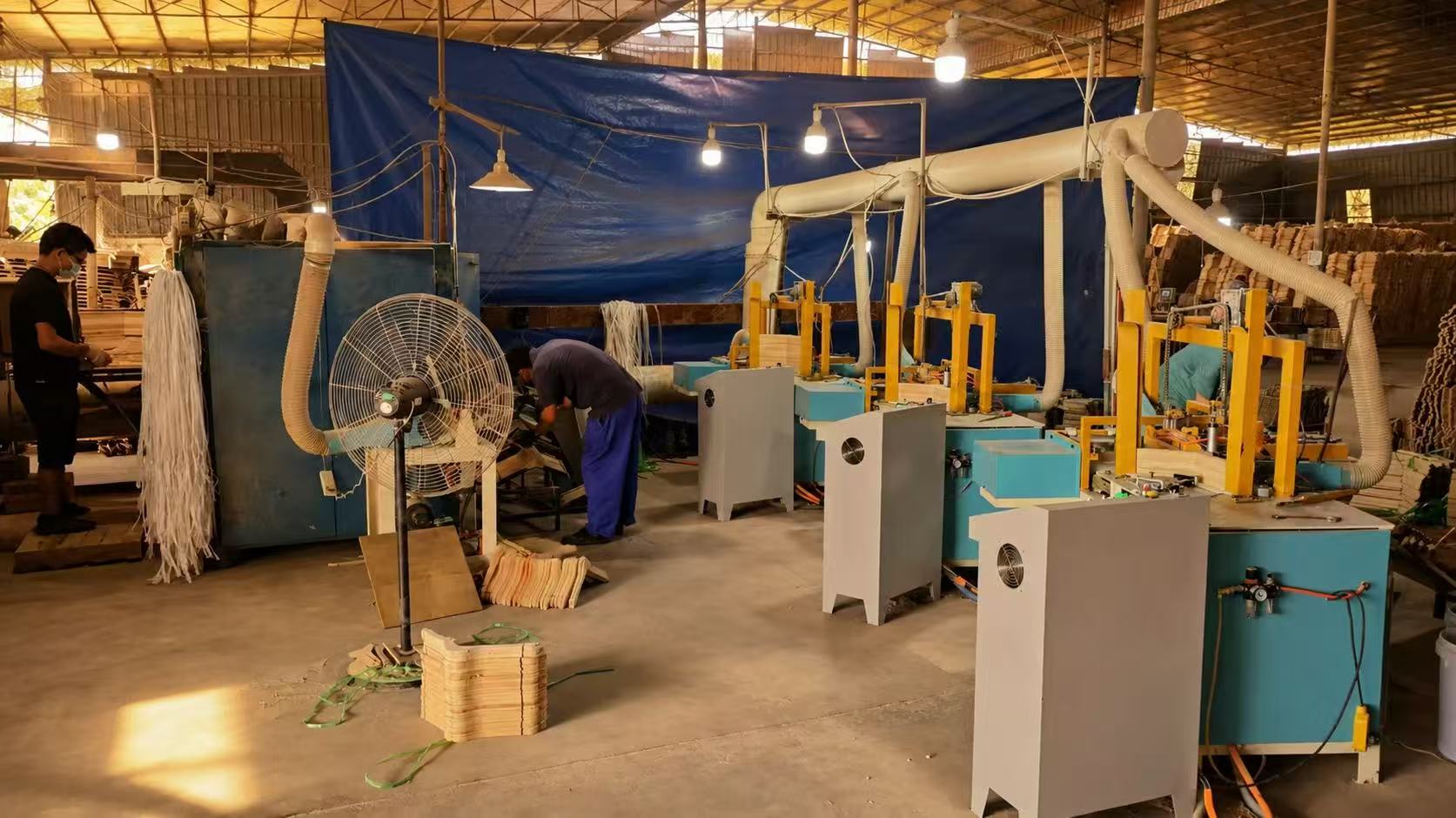 Workshop machinery beside stacks of wooden hanger blanks.