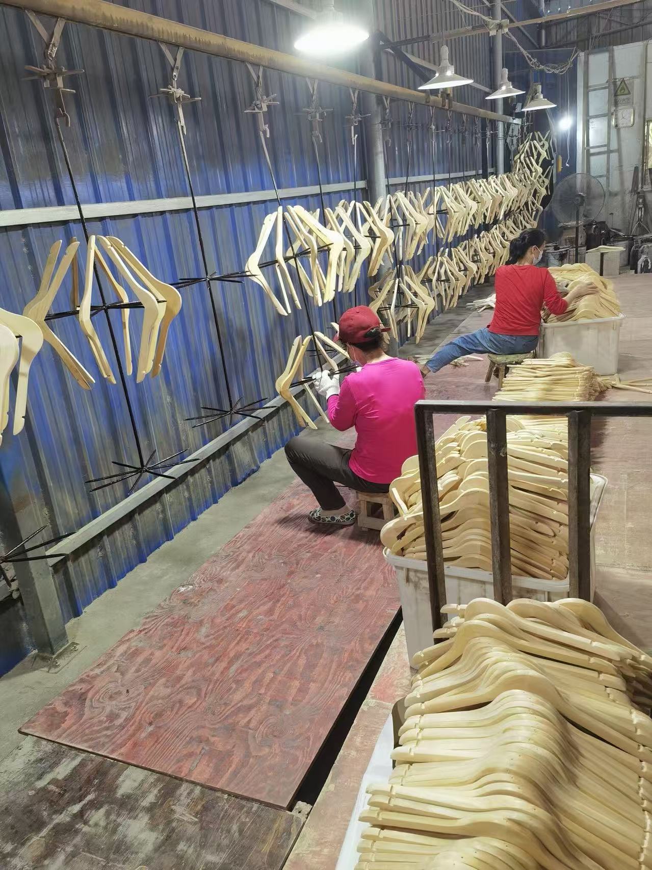 Workers processing wooden hangers on a hanging production line.