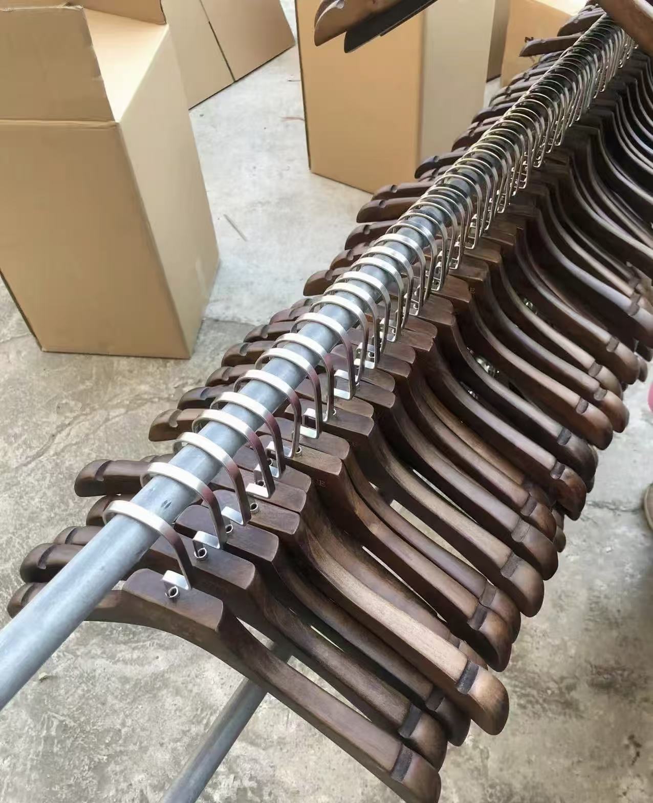 Finished dark wooden hangers arranged on a rail beside cartons.
