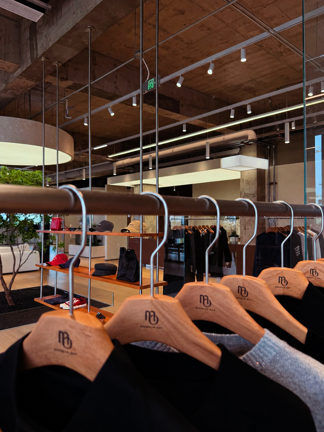 Branded wooden hangers displaying garments in a fashion retail interior.